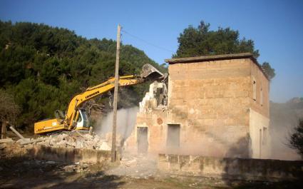Moment en que les màquines de Tragsa han començat a enderrocar el vell edifici de la cala.