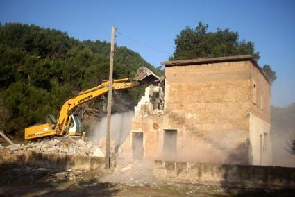 Moment en que les màquines de Tragsa han començat a enderrocar el vell edifici de la cala.
