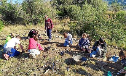Un grup de nins realitzen tasques de manteniment al jaciment.