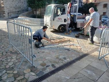 Els treballadors col·loquen la pedra en un tram de paviment.