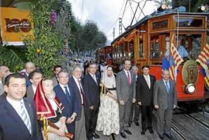 Personalitats i autoritats convidades als actes, davant el tramvia engalanat amb banderes.