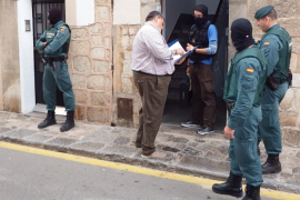 Un lletrat lliura l'ordre d'entrada a un agent de la Policia Judicial just abans d'una de les 16 detencions realitzades en diferents domicilis de Sóller i Port.