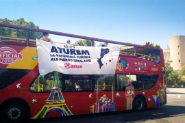Arran penja una pancarta a un bus turístic: 'Aturem la massificació turística als Països Catalans'