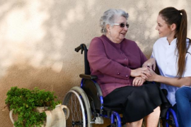 elderly senior woman on wheelchair with nurse outdoor in nursing home hospital garden